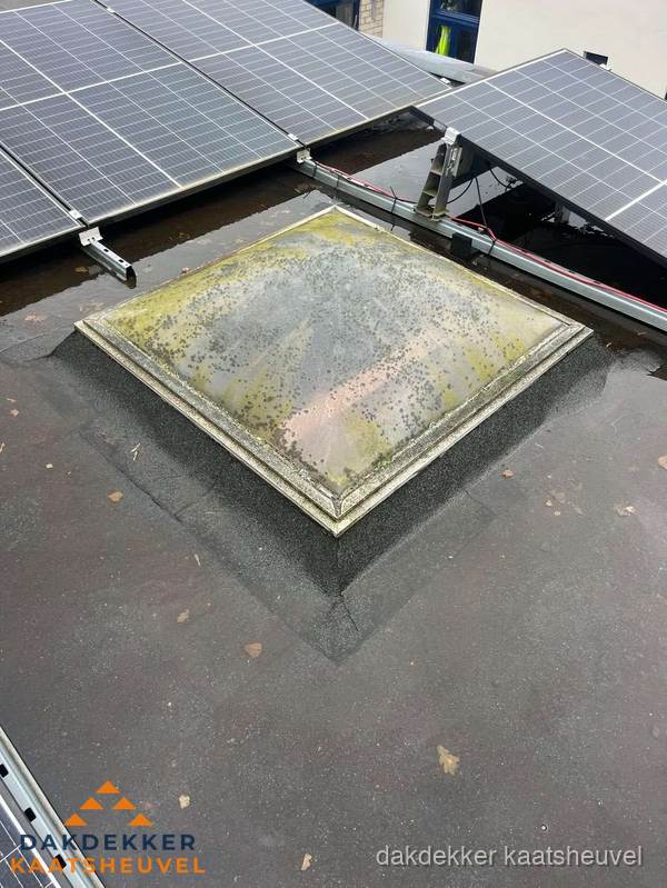 Vervuilde lichtkoepel op plat dak met zonnepanelen in Kaatsheuvel