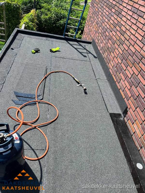 Plat dak met bitumen en brandgereedschap van dakdekkersbedrijf in Kaatsheuvel