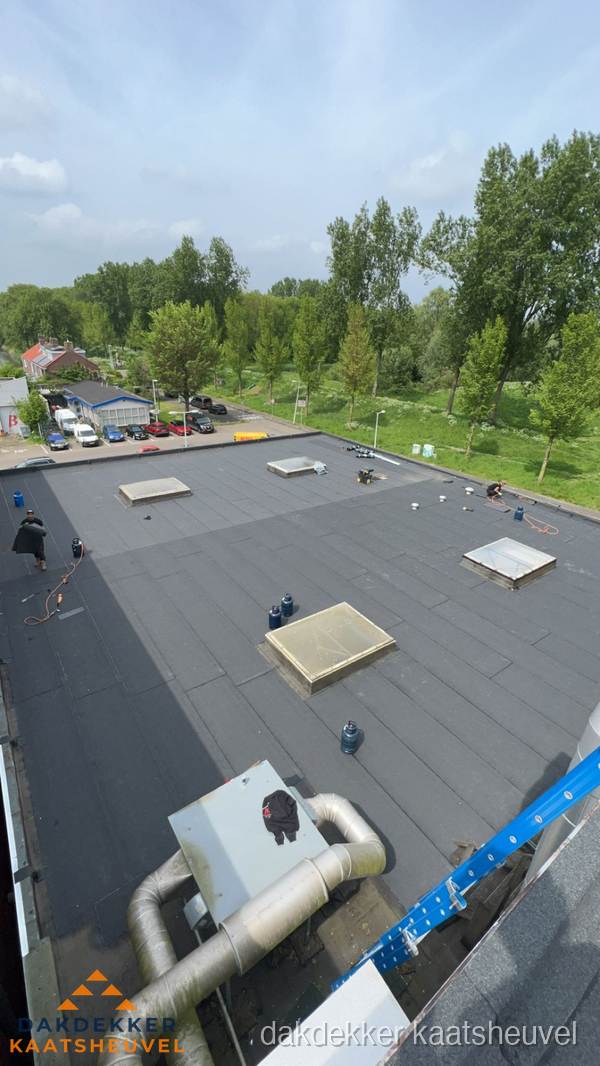 Dakdekker aan het werk op groot plat dak met bitumen in Kaatsheuvel